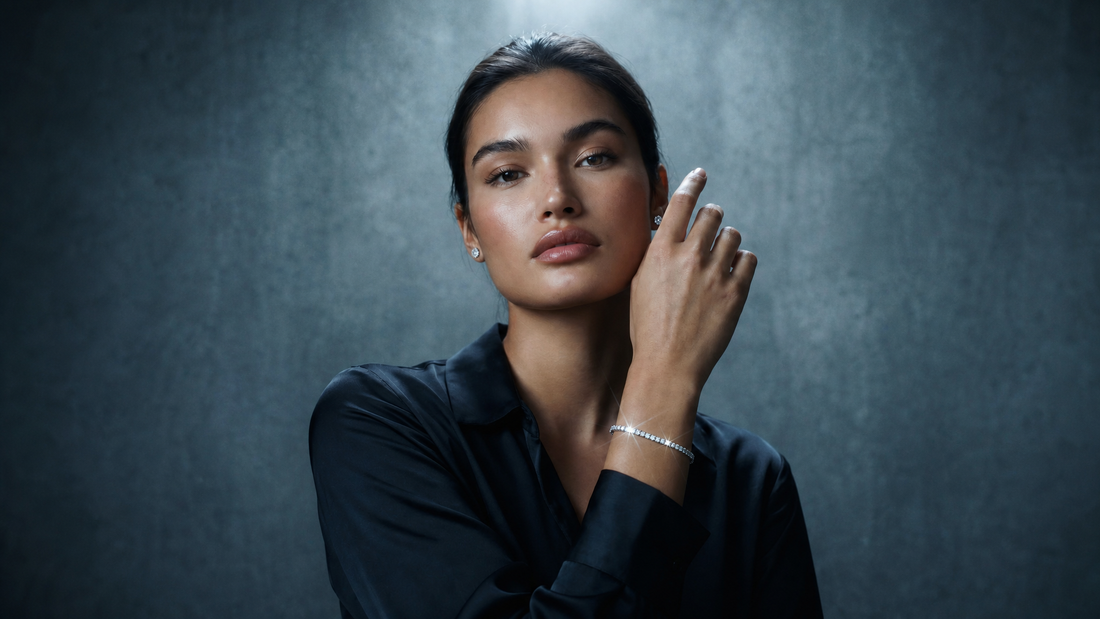 Woman in a dark shirt raising her hand to show a diamond tennis bracelet