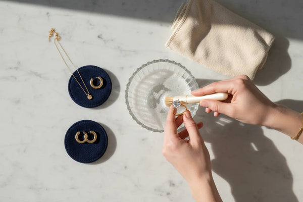 Fine jewelry care setup showing soft brush, mild soap, and gold diamond jewelry ready for at-home cleaning