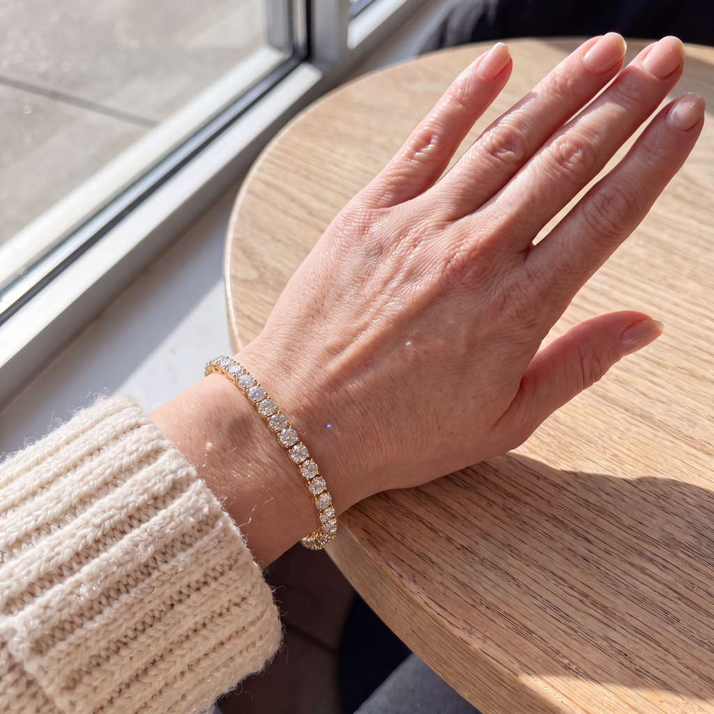 Candid-style photo of a 10 carat lab-grown diamond tennis bracelet in 14K yellow gold worn on the wrist at a sunny café table, AI-generated image — DEEVE