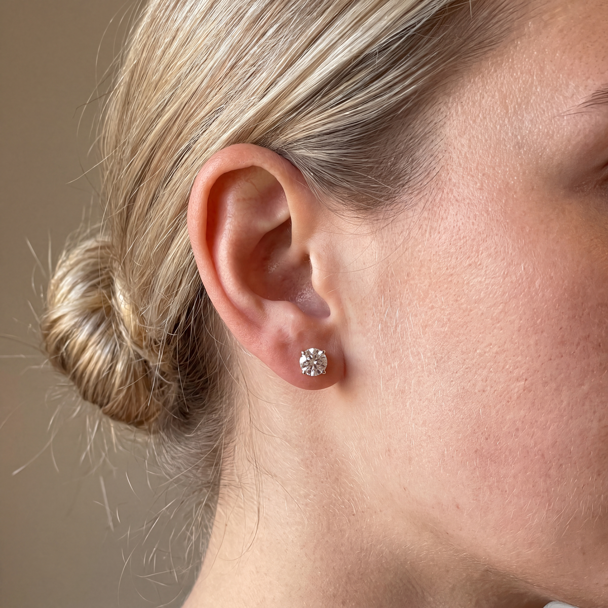 Candid-style close-up of one of a pair of 3 carat lab-grown diamond stud earrings in 14K yellow gold, worn on the ear, AI-generated image — DEEVE