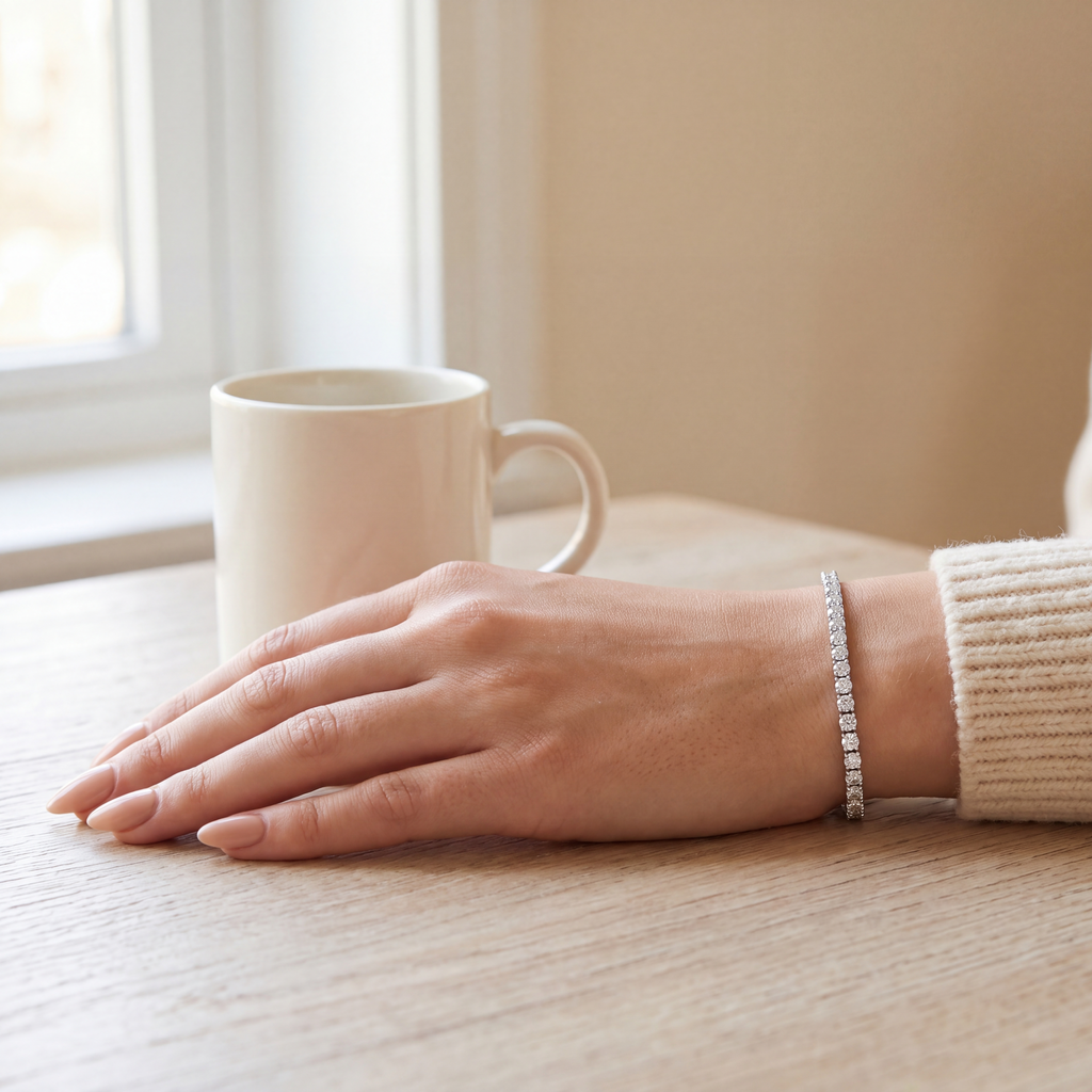 3 carat lab-grown diamond tennis bracelet in 14K white gold worn on the wrist, hand resting on a wooden table beside a mug, AI-generated image — DEEVE