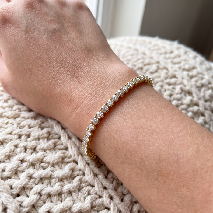 Close-up of a 3 carat lab-grown diamond tennis bracelet in 14K yellow gold worn on the wrist, AI-generated image — DEEVE