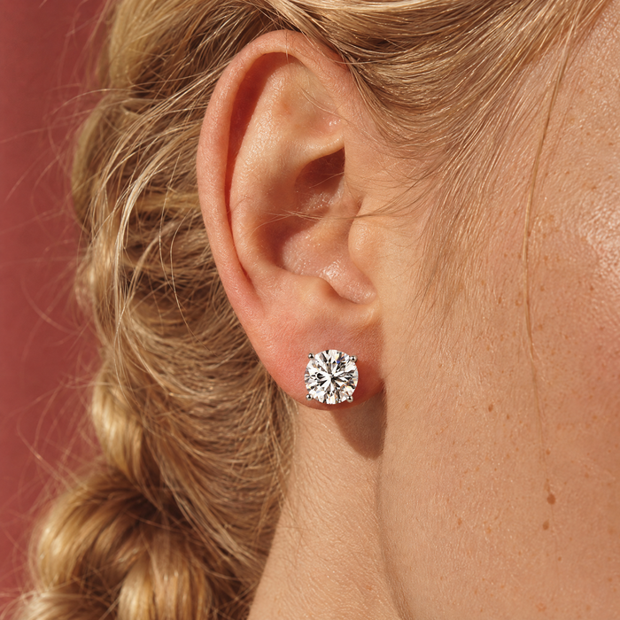 Close-up of one of a pair of 4 carat lab-grown diamond stud earrings in 14K white gold, worn on the ear, AI-generated image — DEEVE