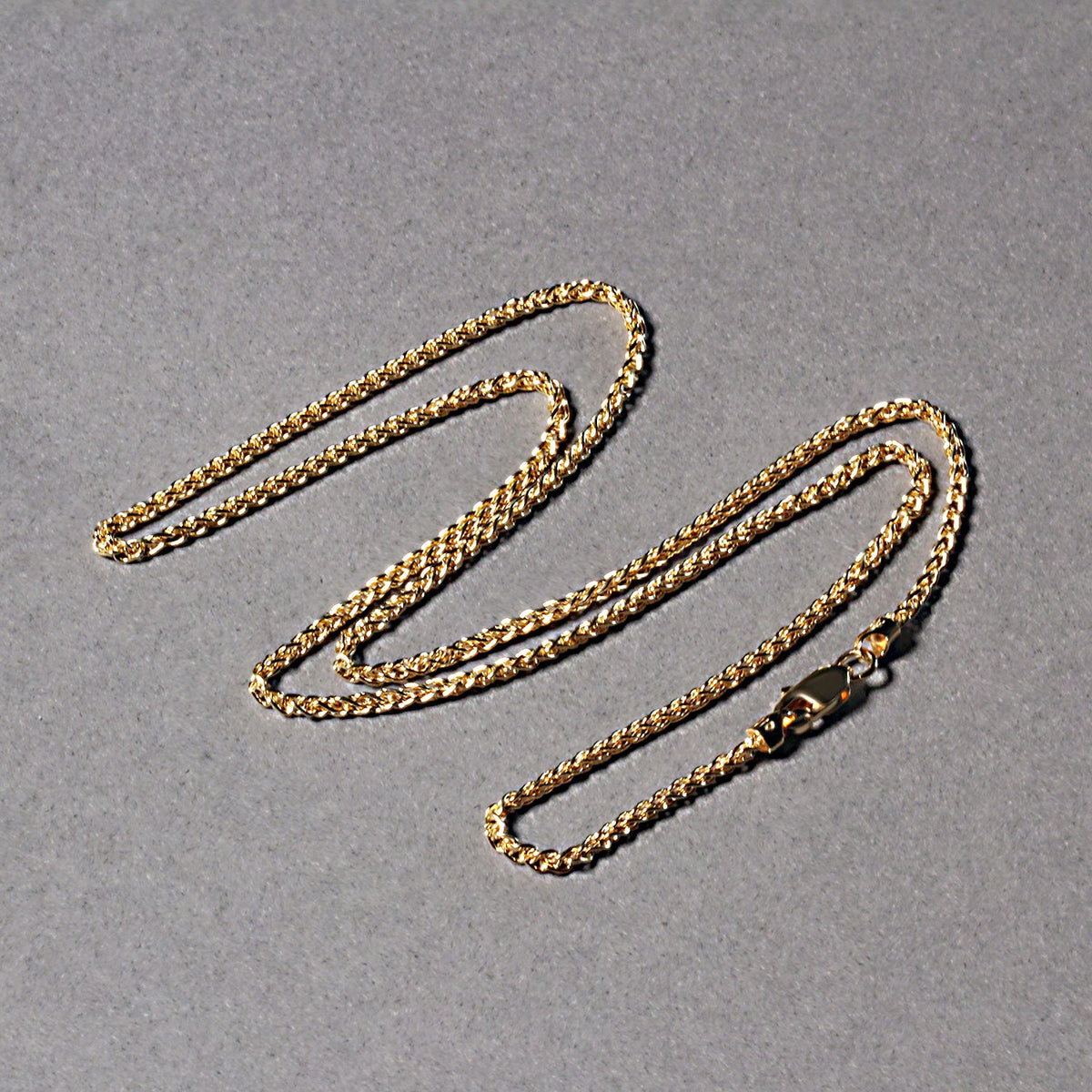 Wheat chain in 14K yellow gold laid out in loops