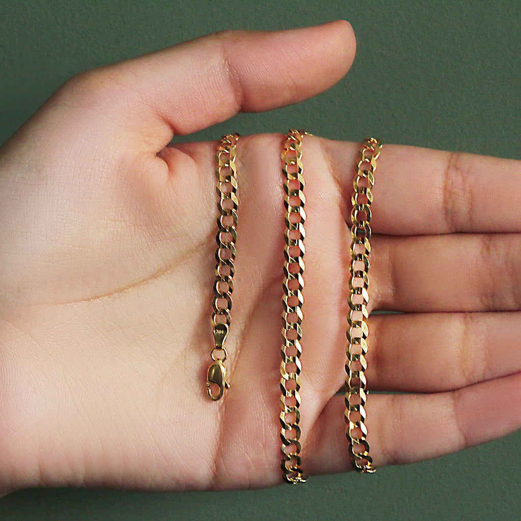 4.70mm curb chain in 14K yellow gold held across an open palm
