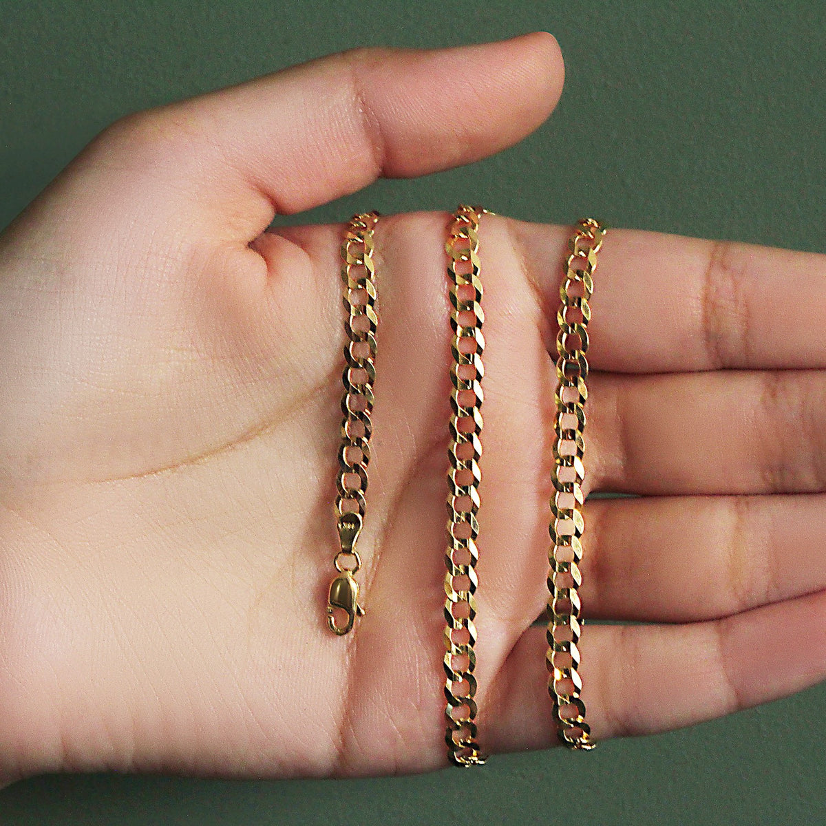 4.70mm curb chain in 14K yellow gold held across an open palm