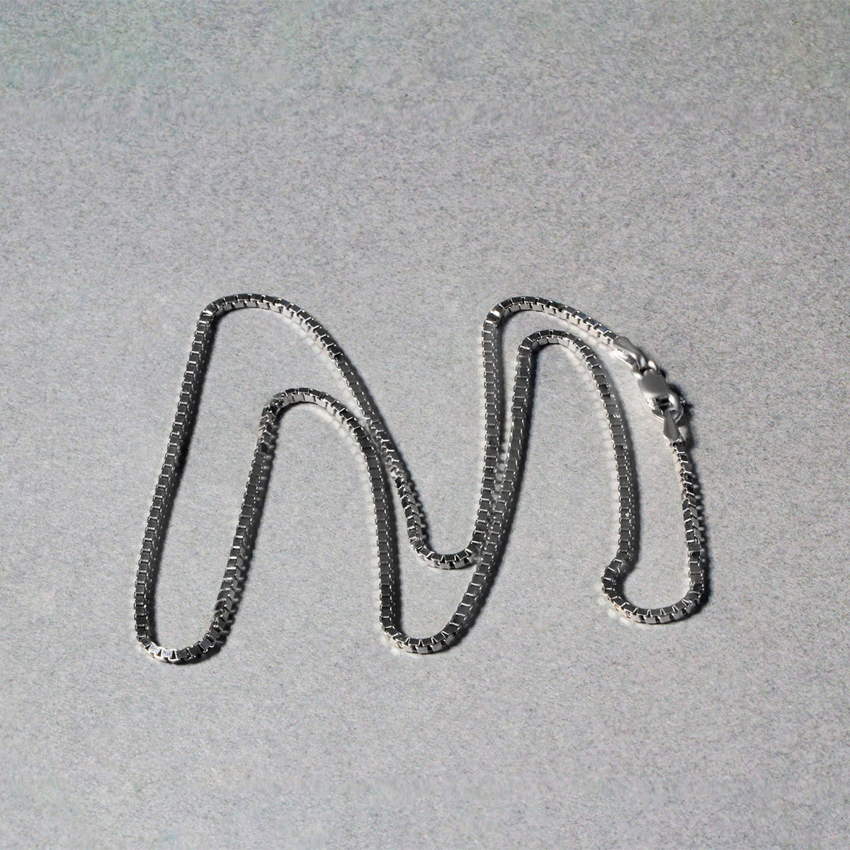Box chain in 14K white gold laid out in loops