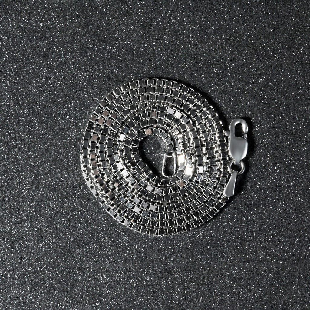 14K white gold box chain, 1.4mm, coiled on a dark surface
