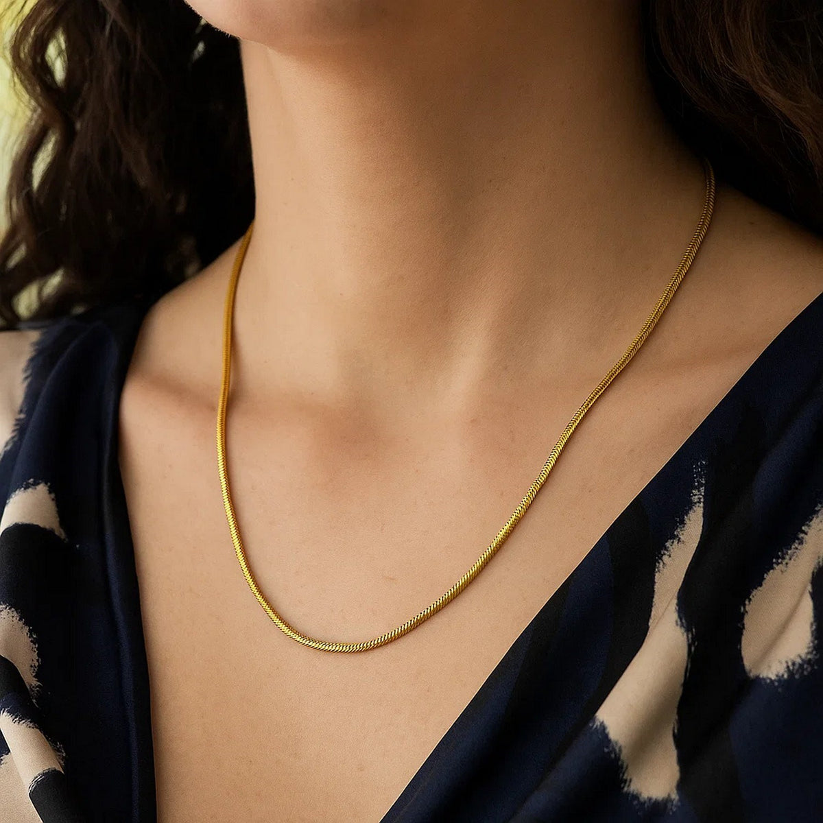 2.60mm snake chain in 14K yellow gold worn at the collarbone with a dark top