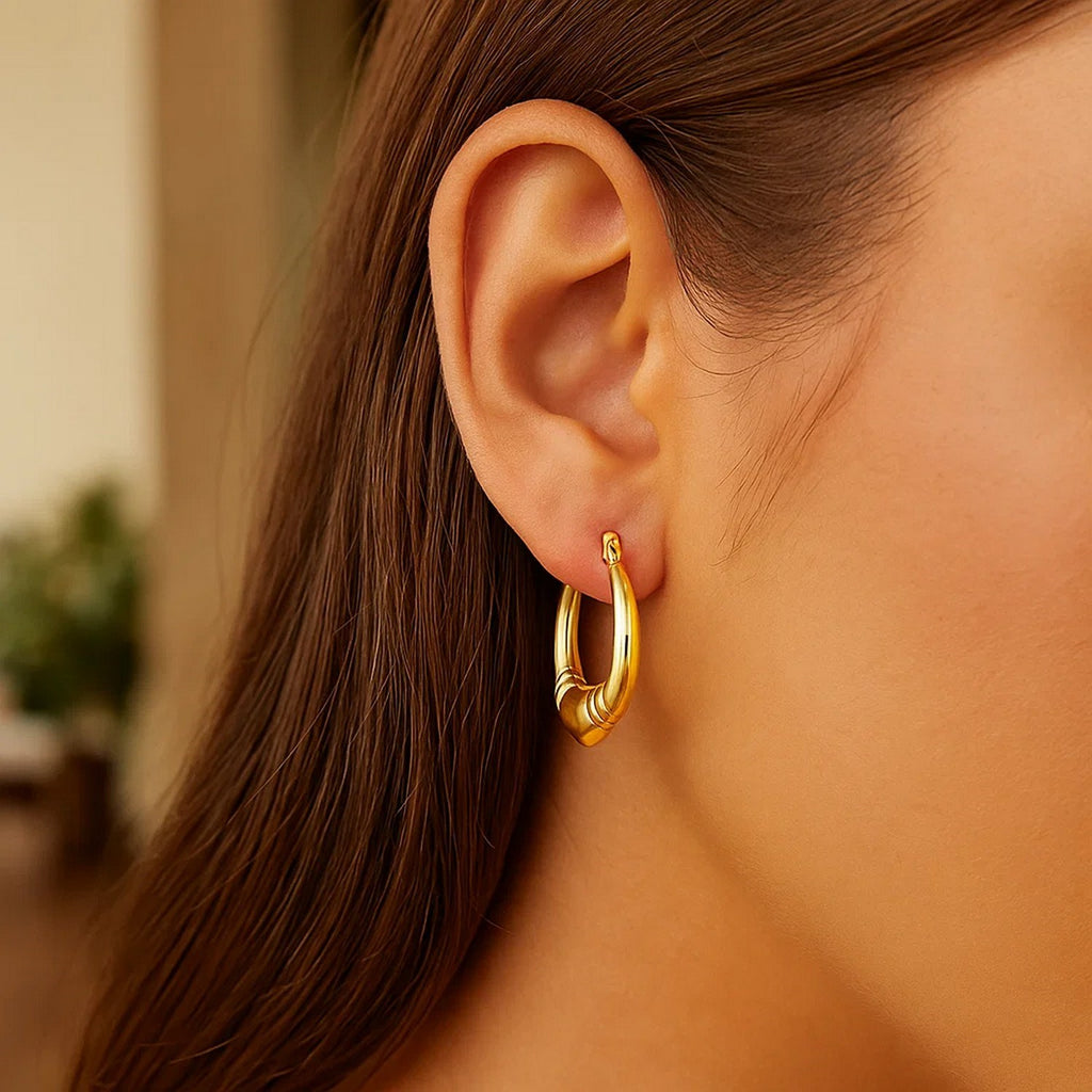 Close-up of a heart-shaped 14K yellow gold hoop on the ear