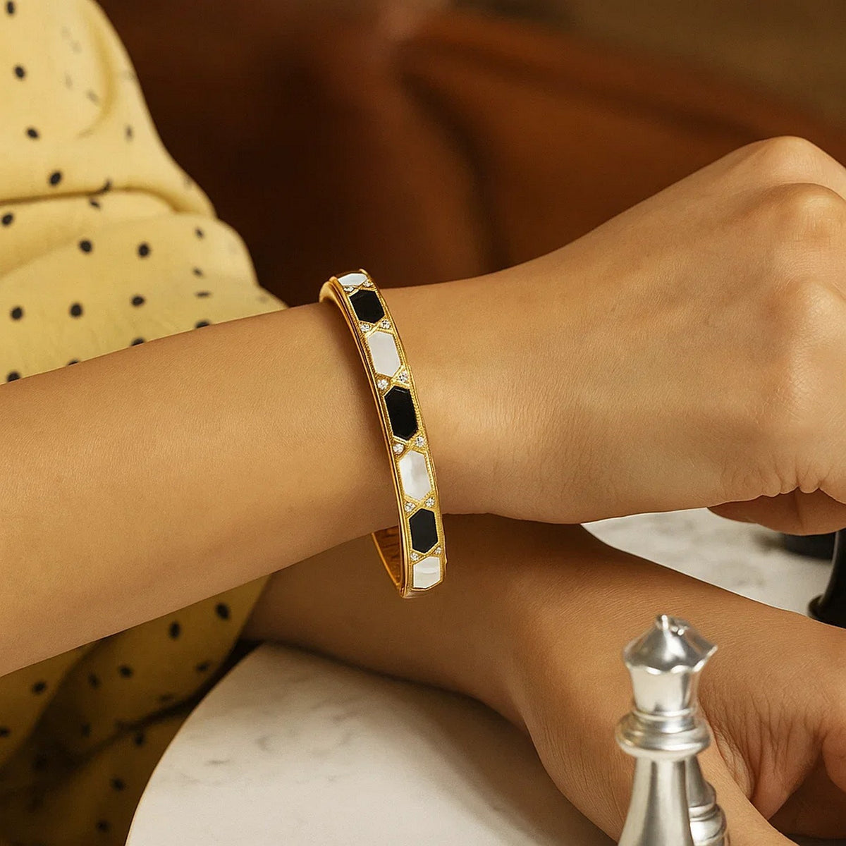 Mother-of-pearl and onyx bangle in 14K yellow gold on the wrist
