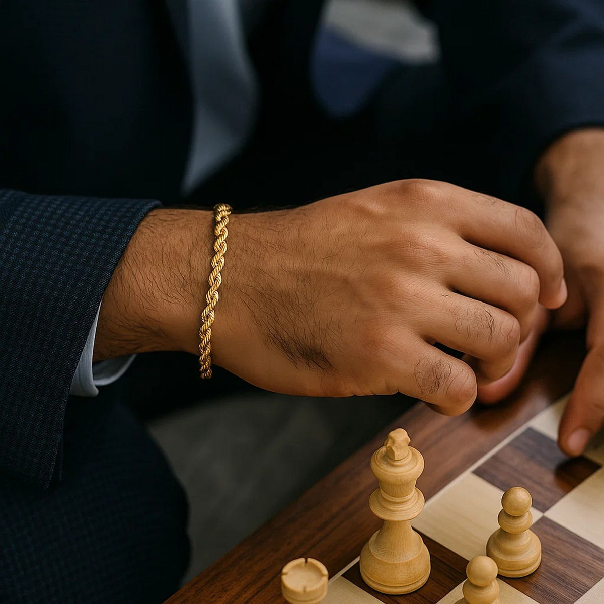Man in a navy suit playing chess, rope bracelet on his wrist