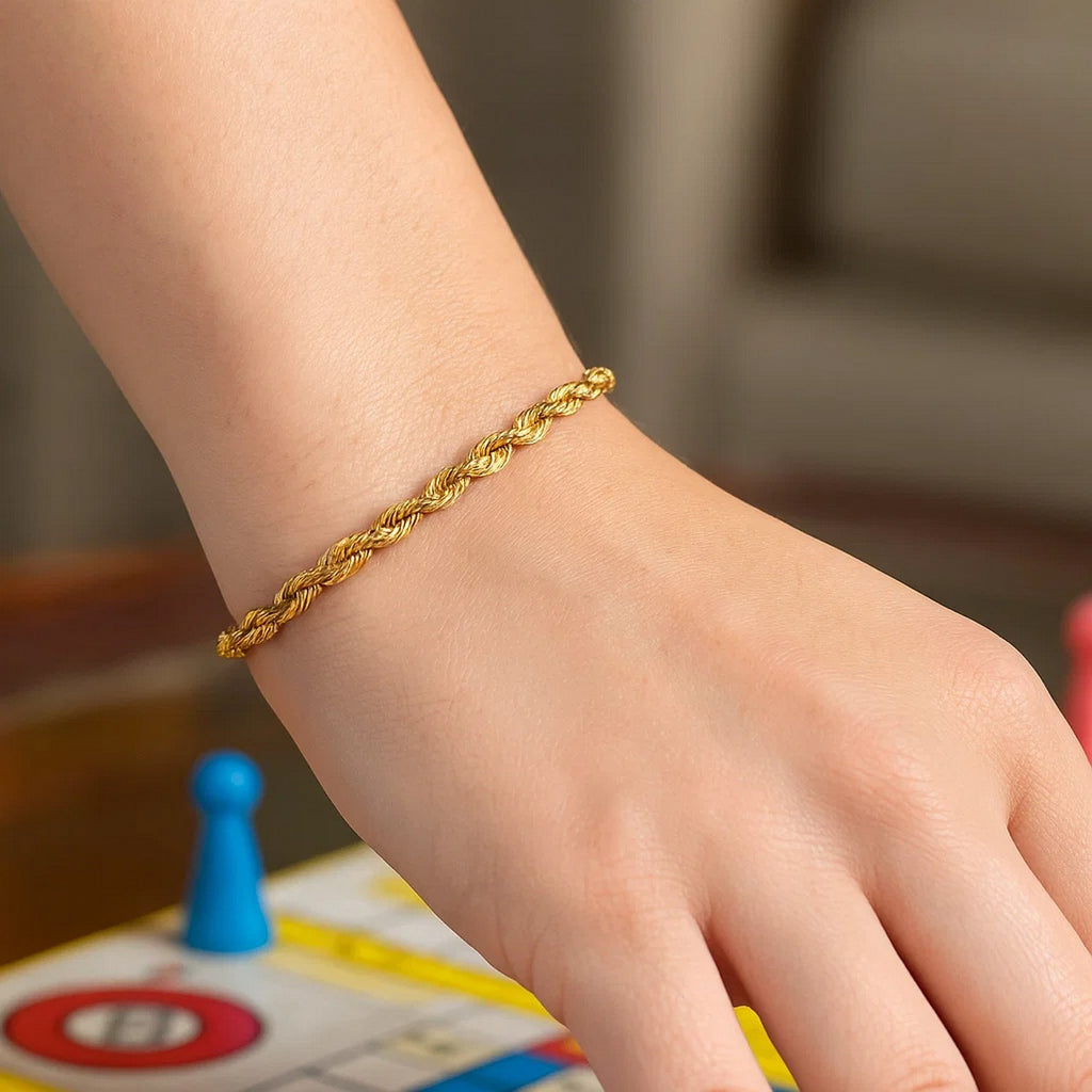 Rope bracelet in 14K yellow gold on a wrist over a board game