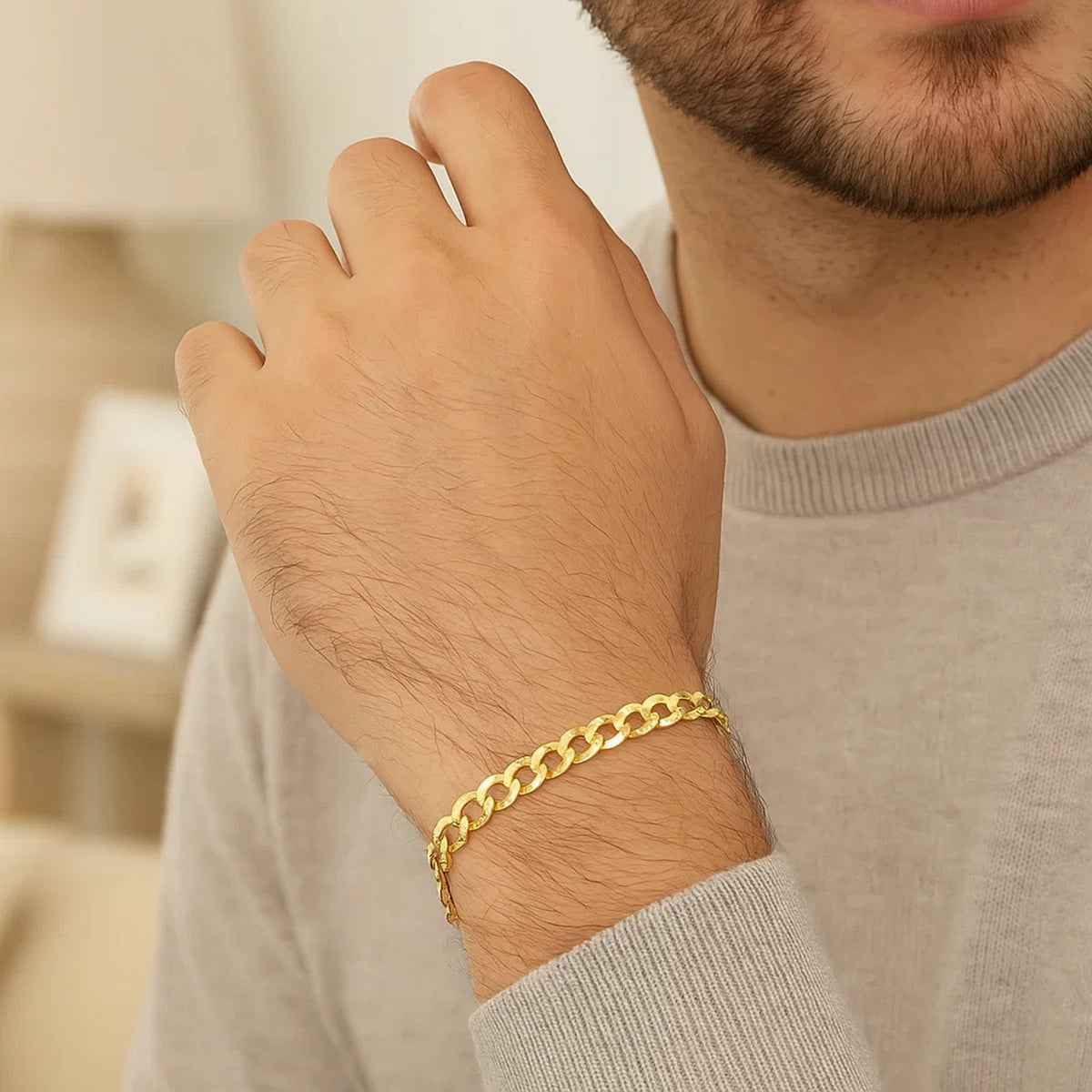Bearded man in a grey sweater wearing a yellow gold curb bracelet