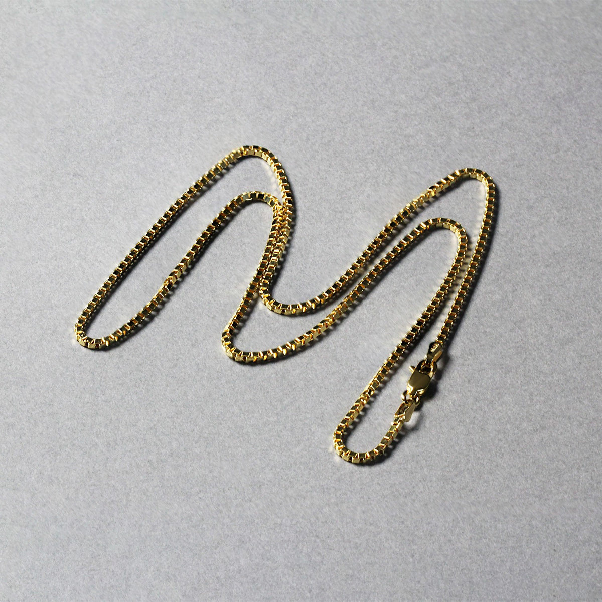Box chain in 14K yellow gold laid out in loops