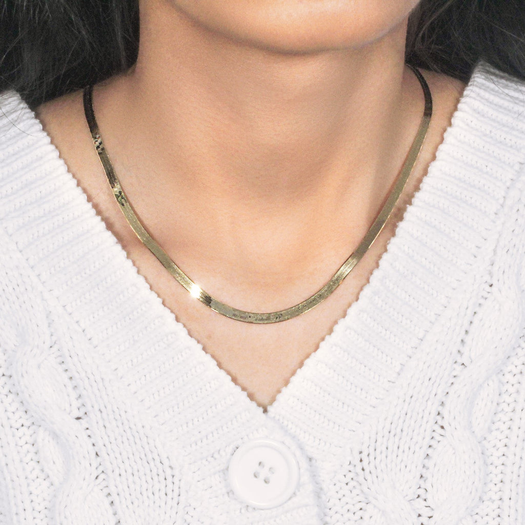 Herringbone necklace in 14K yellow gold worn with a white cable-knit cardigan