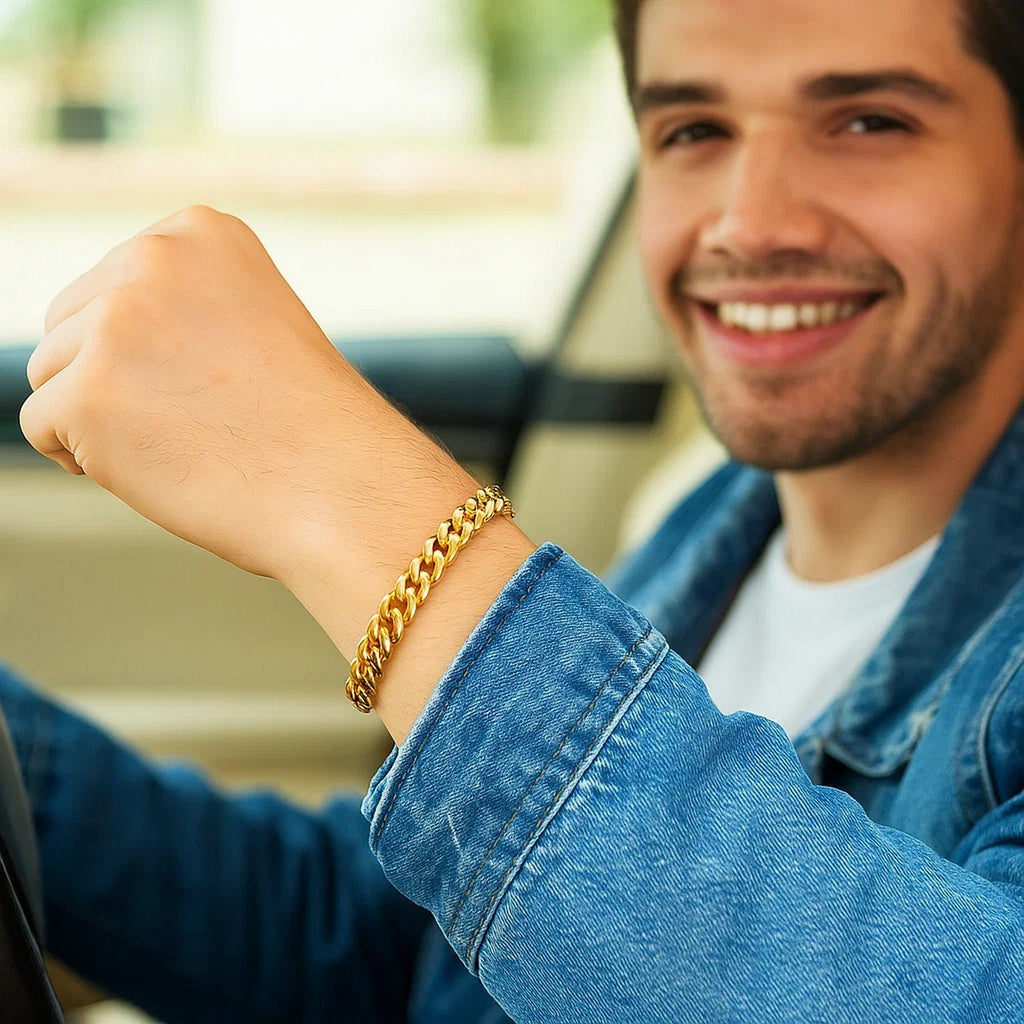 Man driving with a 14K yellow gold Miami Cuban bracelet on his raised wrist
