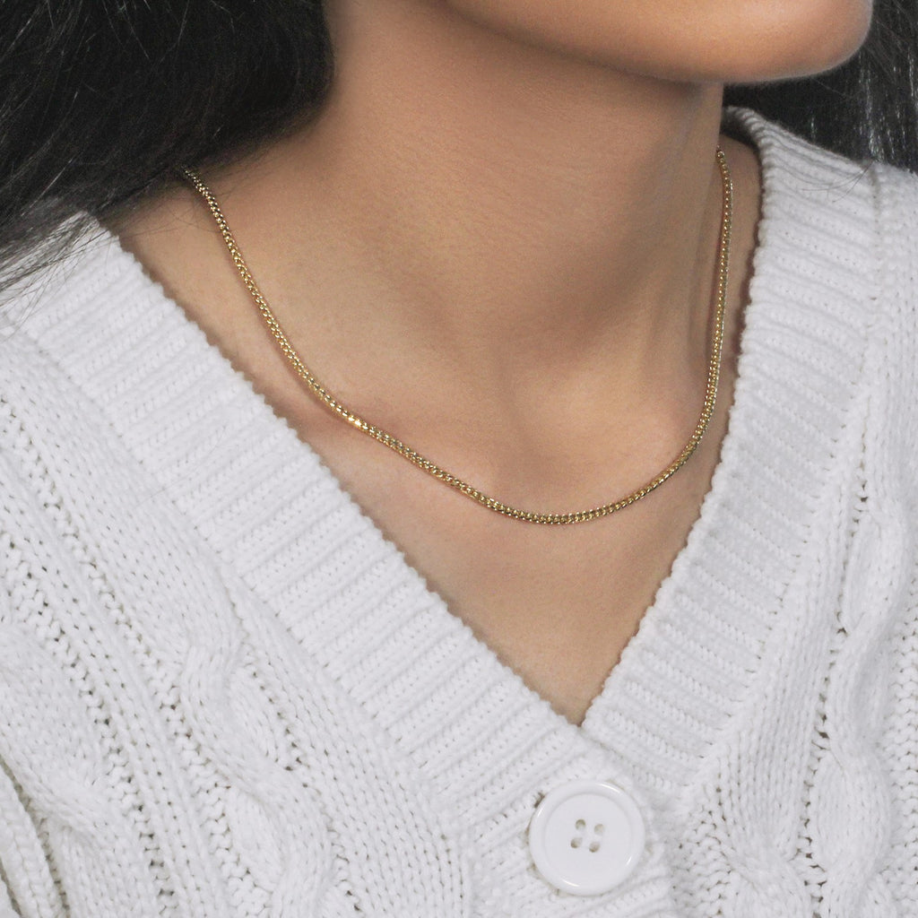 Franco chain in 14K yellow gold worn close to the neck with a white cardigan