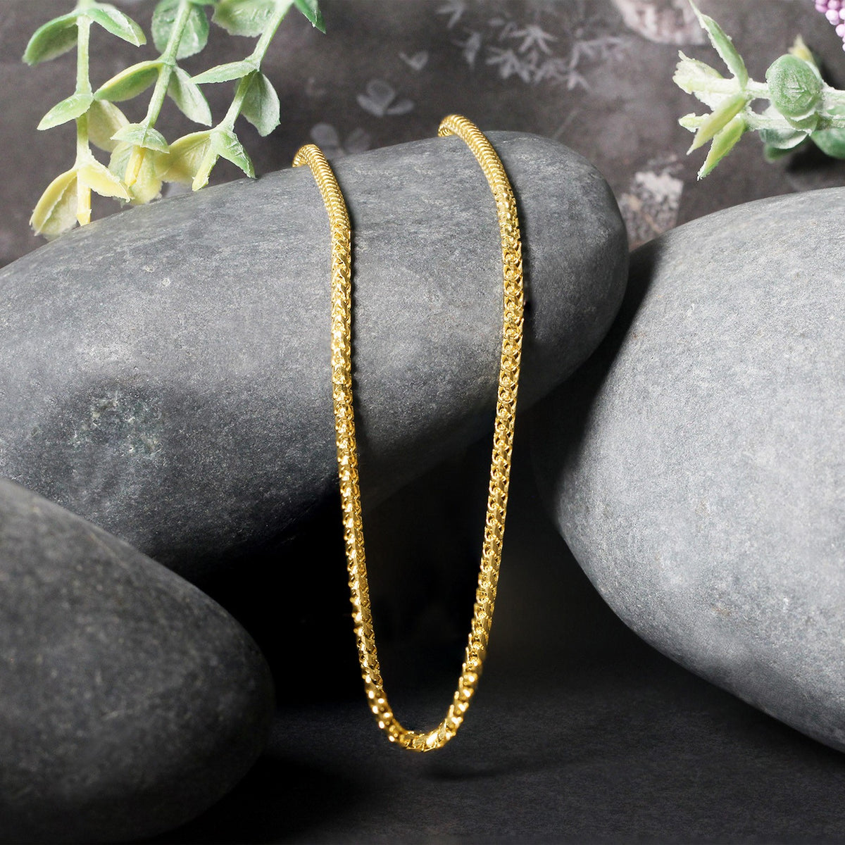 Franco chain in 14K yellow gold draped over two stones