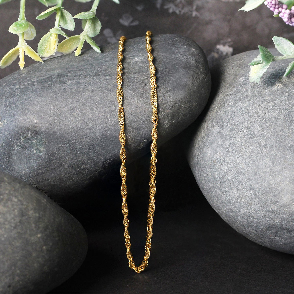 Singapore chain in 14K yellow gold draped over two stones