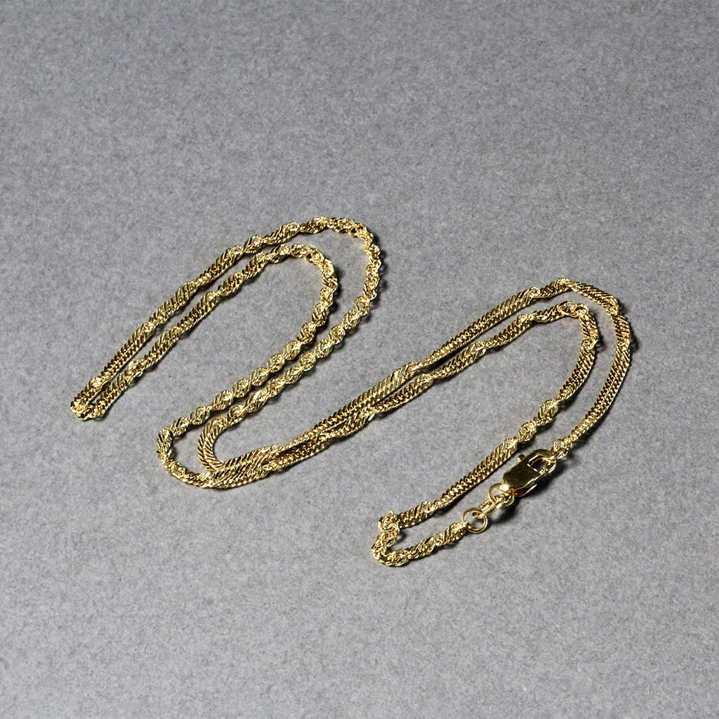 Singapore chain in 14K yellow gold laid out in loops