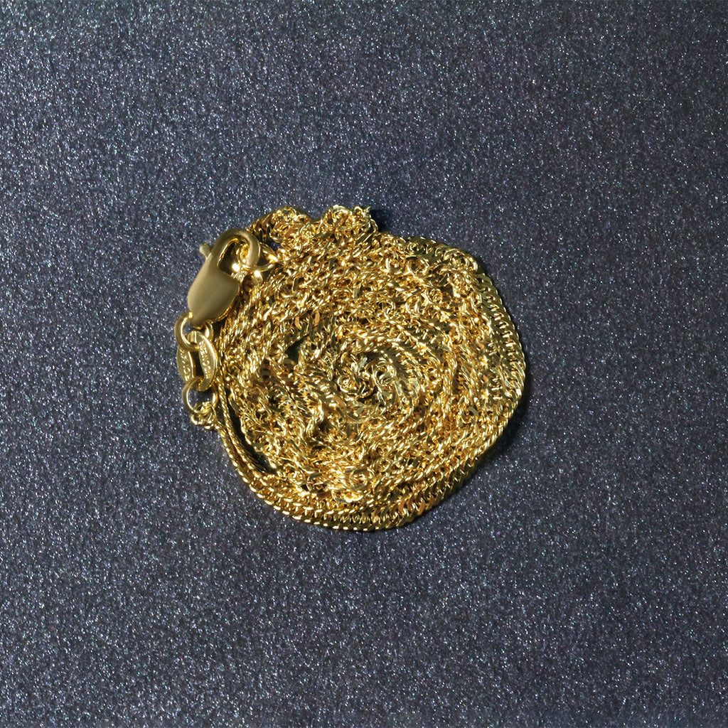 14K yellow gold Singapore chain, 1.80mm, coiled on a dark surface