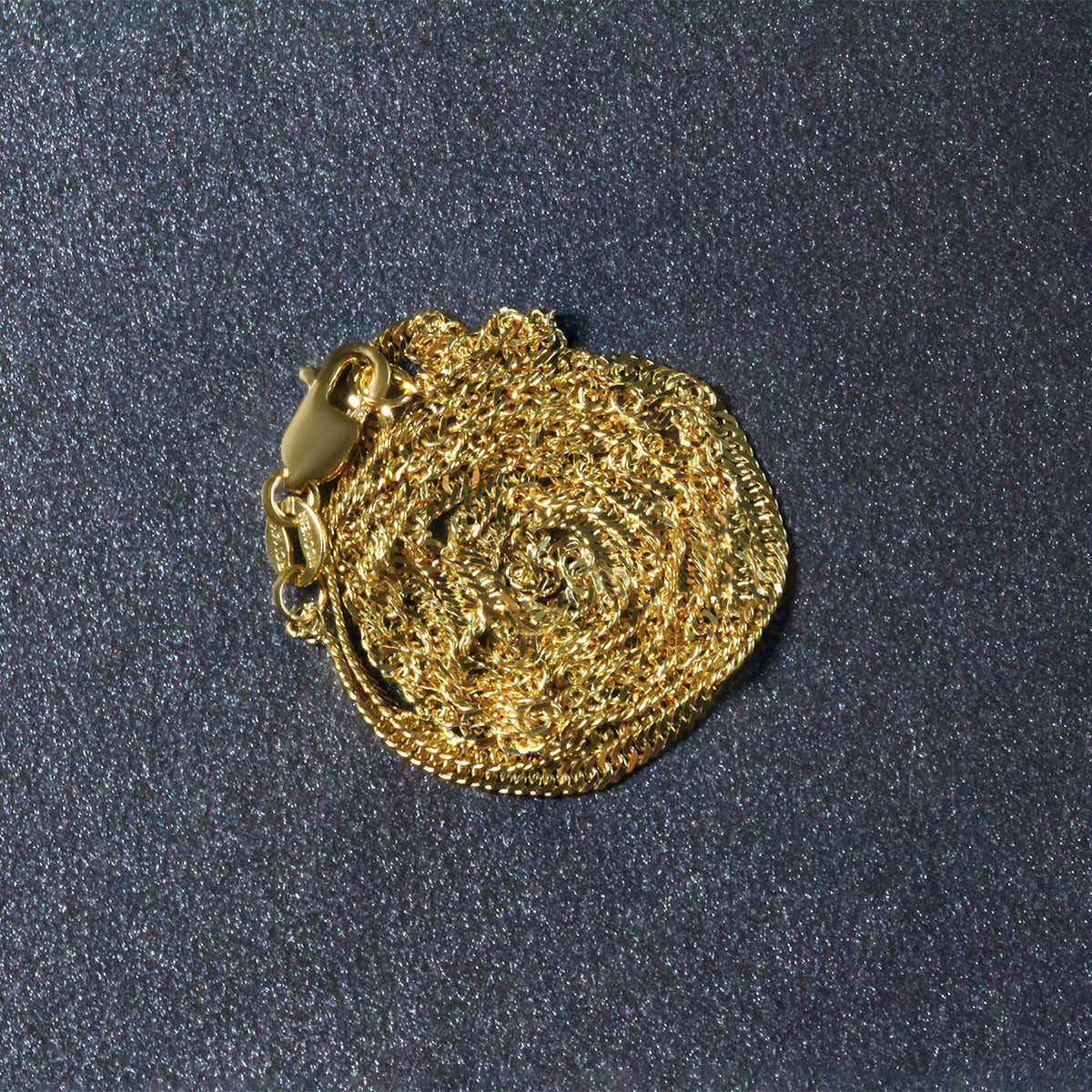 14K yellow gold Singapore chain, 1.80mm, coiled on a dark surface
