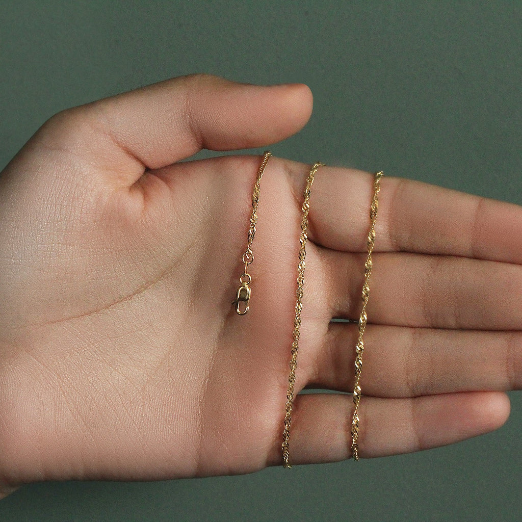 1.80mm Singapore chain in 14K yellow gold held across an open palm