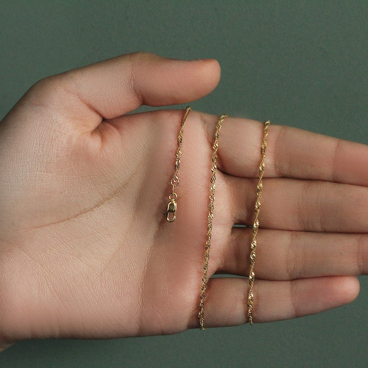 1.80mm Singapore chain in 14K yellow gold held across an open palm