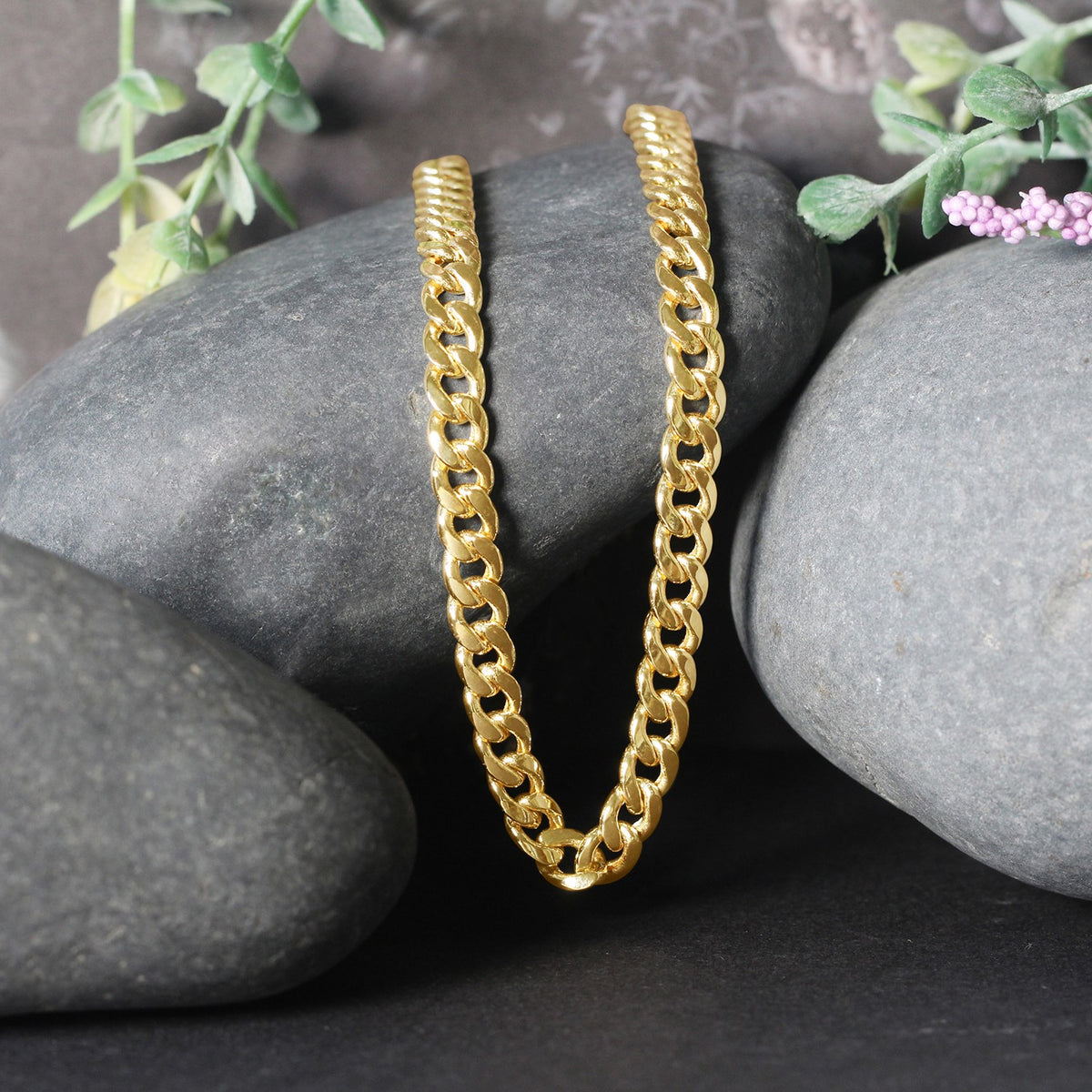 Miami Cuban chain in 14K yellow gold draped over two stones