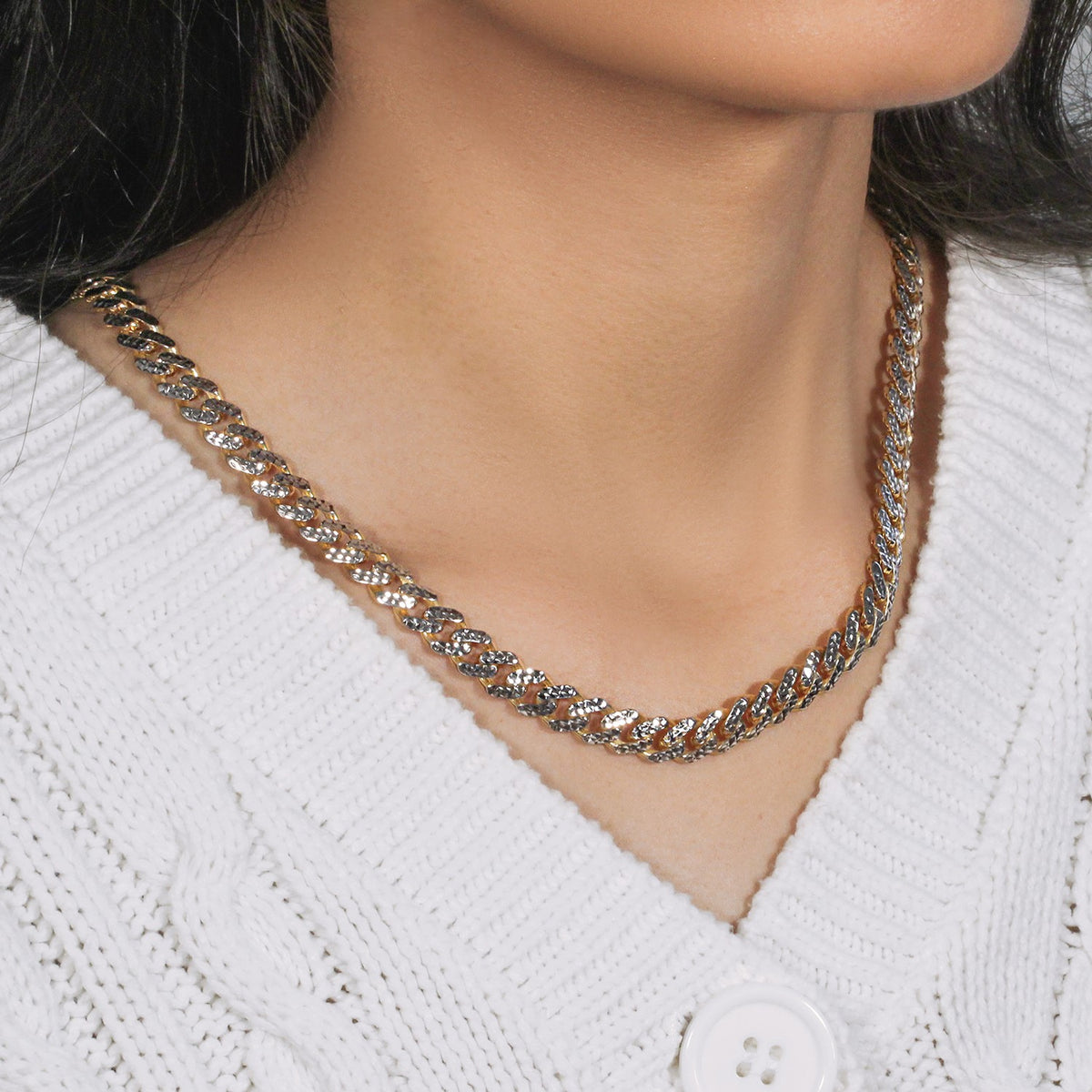 Two-tone Miami Cuban chain seen from the side, worn with a white cardigan