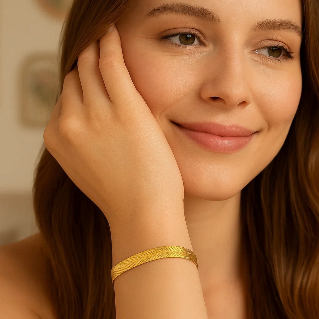 Woman with auburn hair wearing a flat 14K yellow gold herringbone bracelet