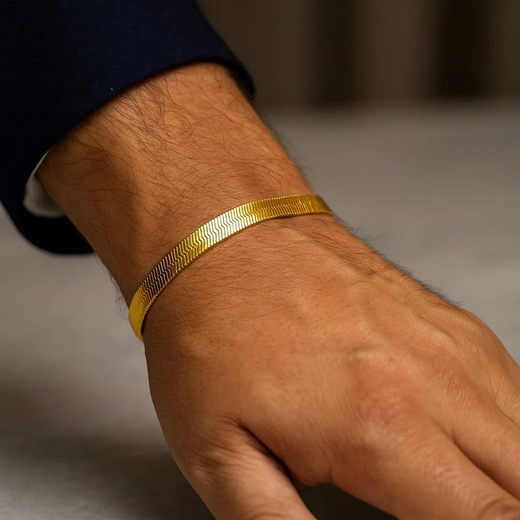 Wide herringbone bracelet in 14K yellow gold on a man's wrist with a navy sleeve