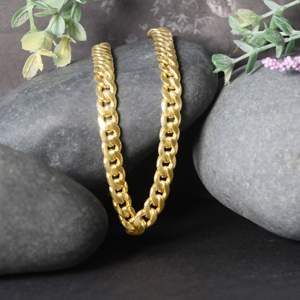 Miami Cuban chain in 14K yellow gold draped over two stones
