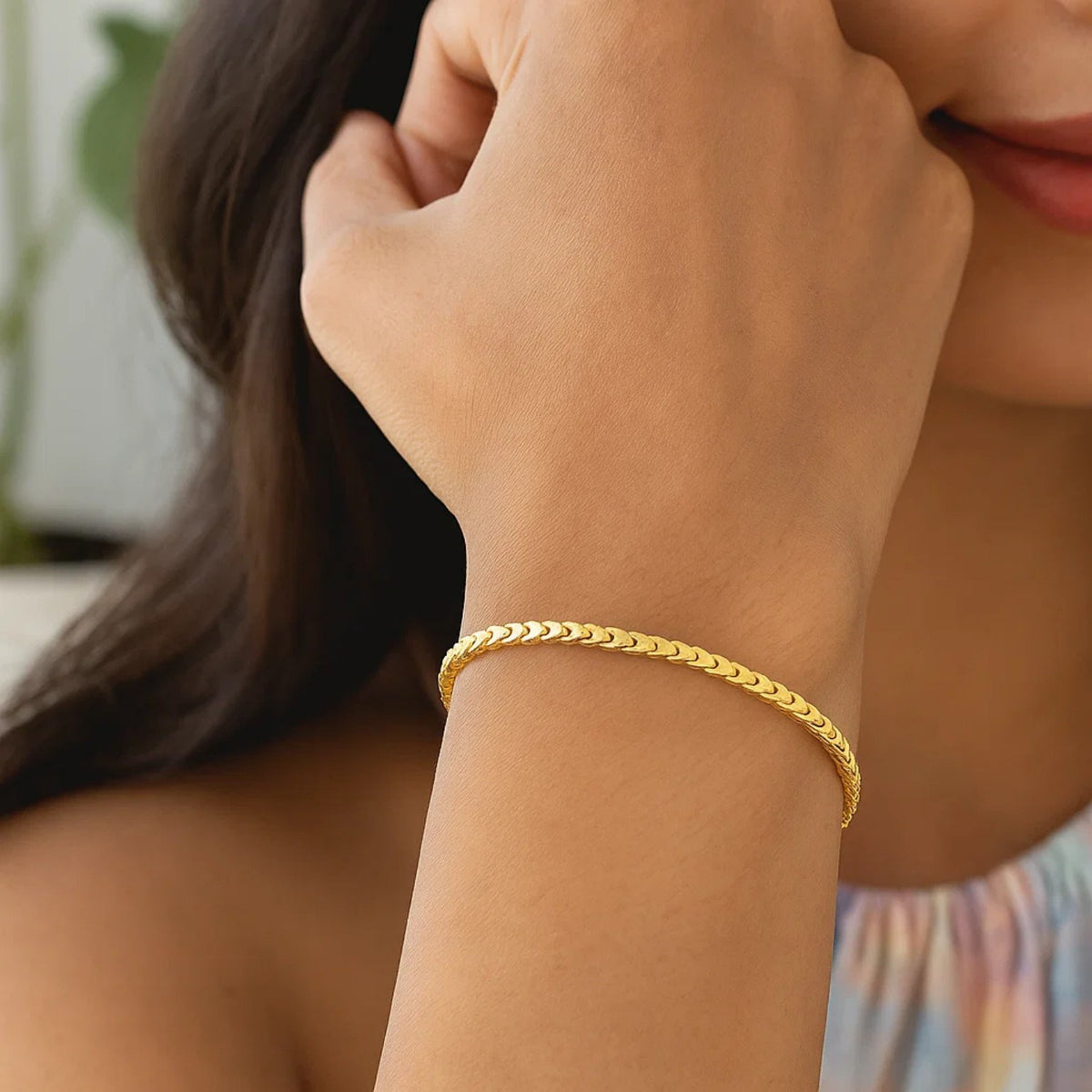 Gold bracelet worn by a woman with long dark hair