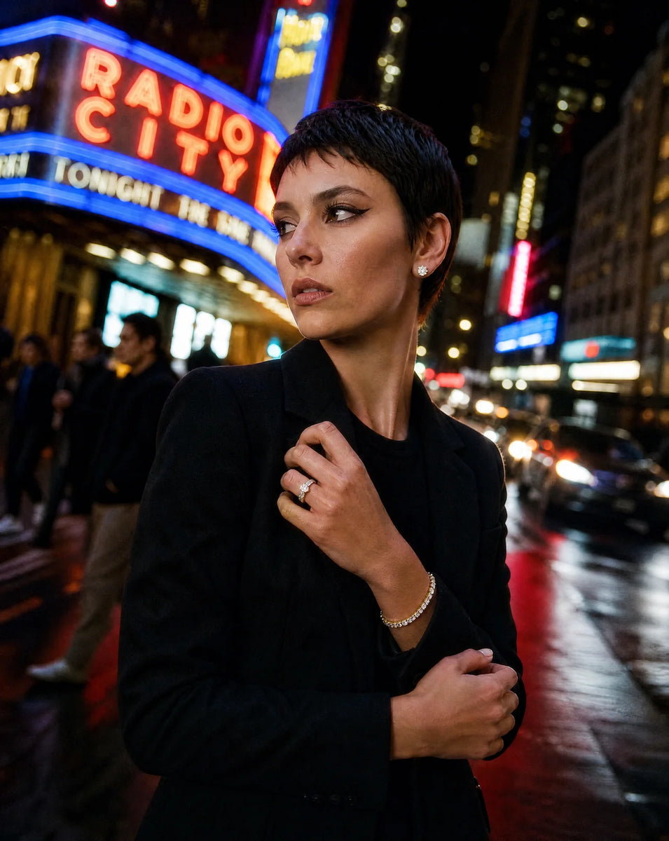 Deeve Canada's model wearing complete IGI lab grown diamond set in a black coat standing in front of Radio City Music Hall NY at night.