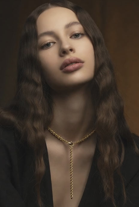 female model wearing a 14k solid gold link chain lariat necklace in a brown background wearing black dress 