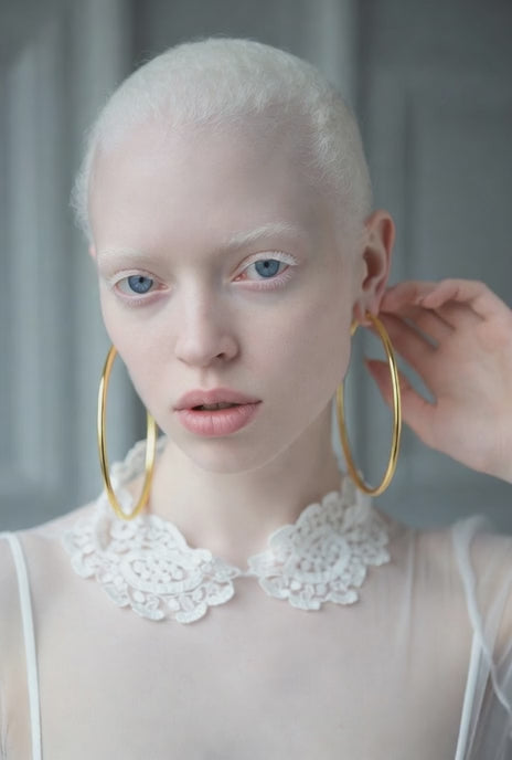 albino supper model promoting a large everyday luxury 14k solid gold polished hoop earrings