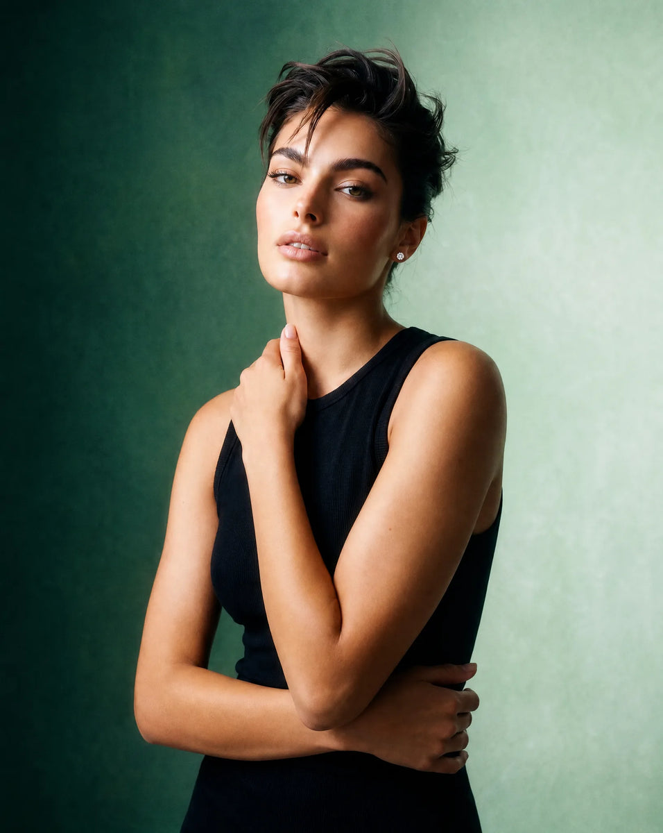 Deeve Canada model promoting a 2 carat igi certified lab grown diamond stud earrings in 14k white gold in a black sleeveless dress against a green background