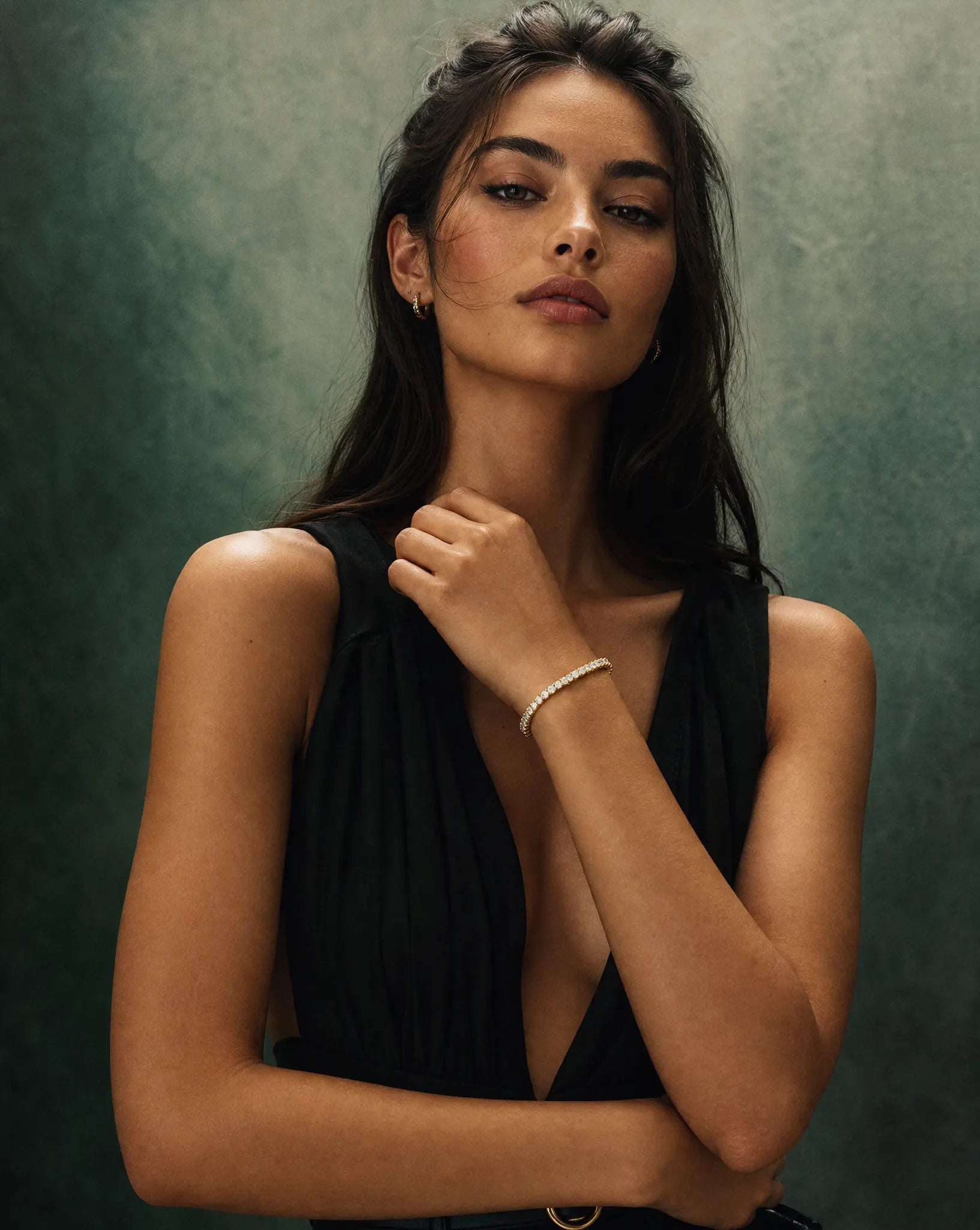 model wearing a 10 carat lab grown diamond bracelet in 14K yellow gold from Deeve Canada diamond collection a black sleeveless top against a textured green background