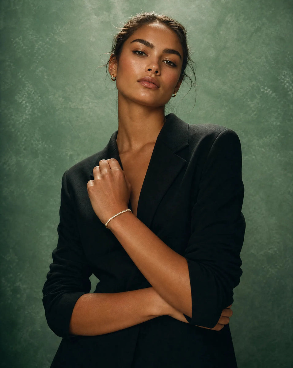 Deeve Canada model wearing 4 carat lab grown diamond tennis bracelet in 14K yellow gold a black blazer against a textured green background