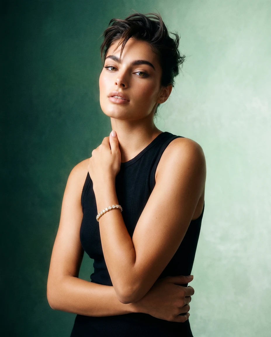 A model promoting a lab grown diamond tennis bracelet from Deeve Canada wearing a black sleeveless top against a green background