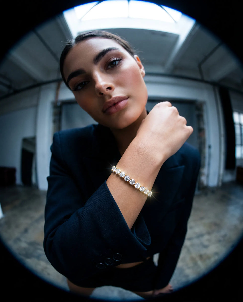 Deeve Canada model wearing 10 carat lab grown diamond tennis bracelet in 14K yellow gold in black coat  in an indoor setting