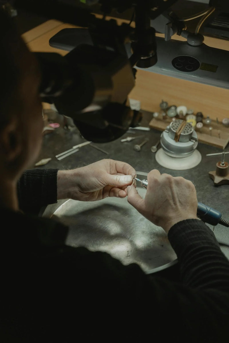 Deeve's master goldsmith working on a 14k gold ring with a microscope in a workshop setting lab grown diamonds